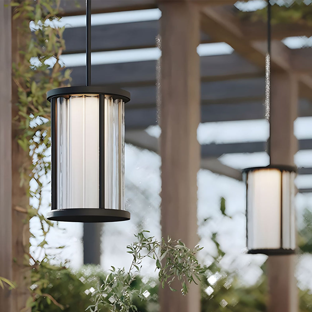 Outdoor dining area enhanced by suspended cylindrical light fixture creating warm atmospheric lighting