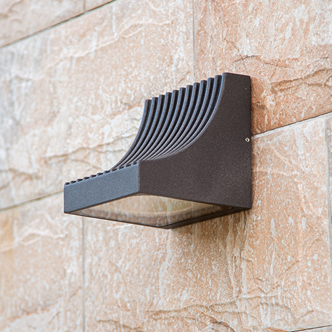 Traditional brass wall lantern with frosted glass shade mounted on stone exterior wall