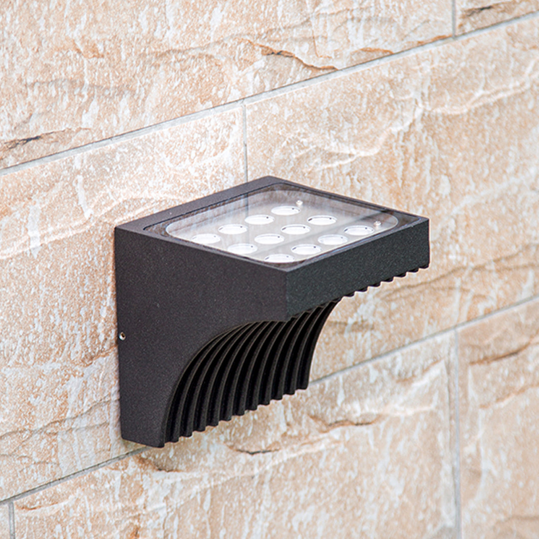 Traditional brass wall lantern with frosted glass shade mounted on stone exterior wall