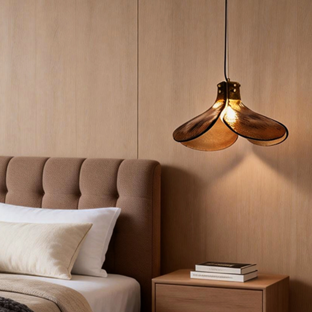 Amber glass pendant light providing soft illumination above a modern bed.