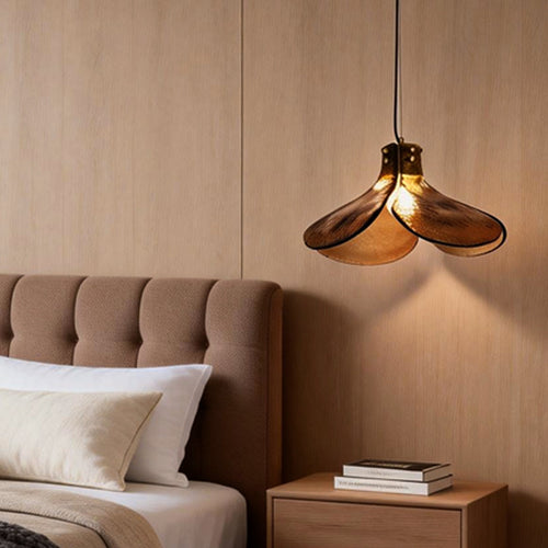 Amber glass pendant light providing soft illumination above a modern bed.
