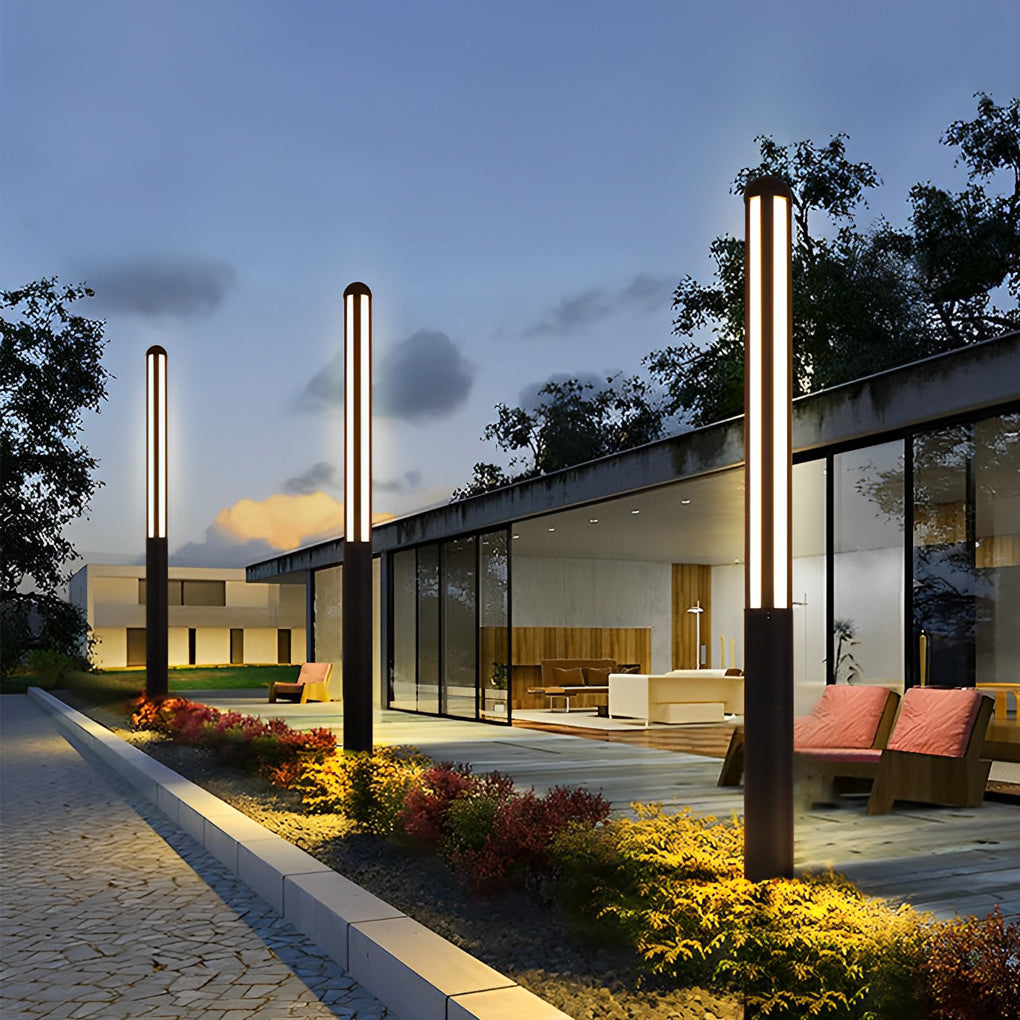 Tall garden bollard light providing ambient lighting for modern outdoor seating area.