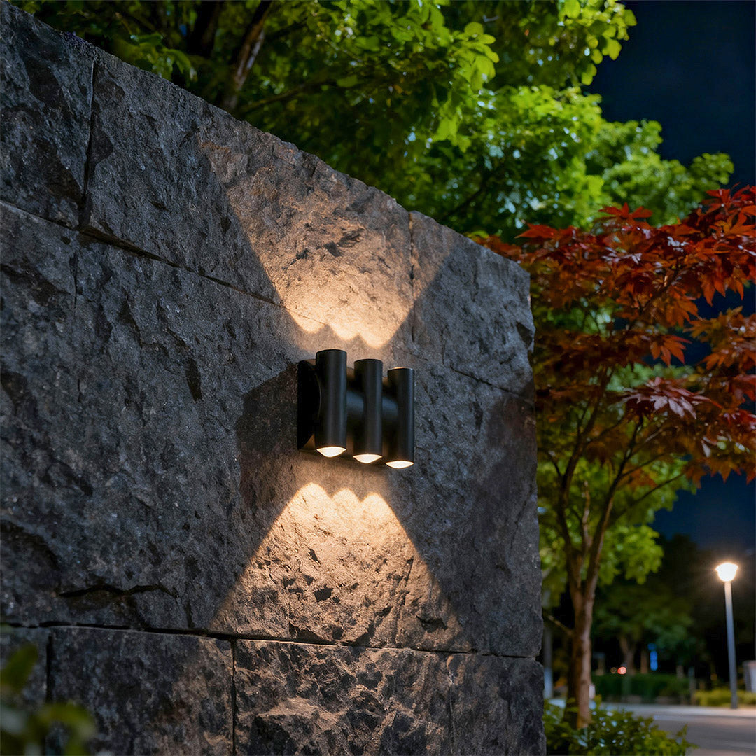Architectural up down lighting wall lights featuring glass shade chandelier styling providing dramatic accent lighting on textured wall at night.