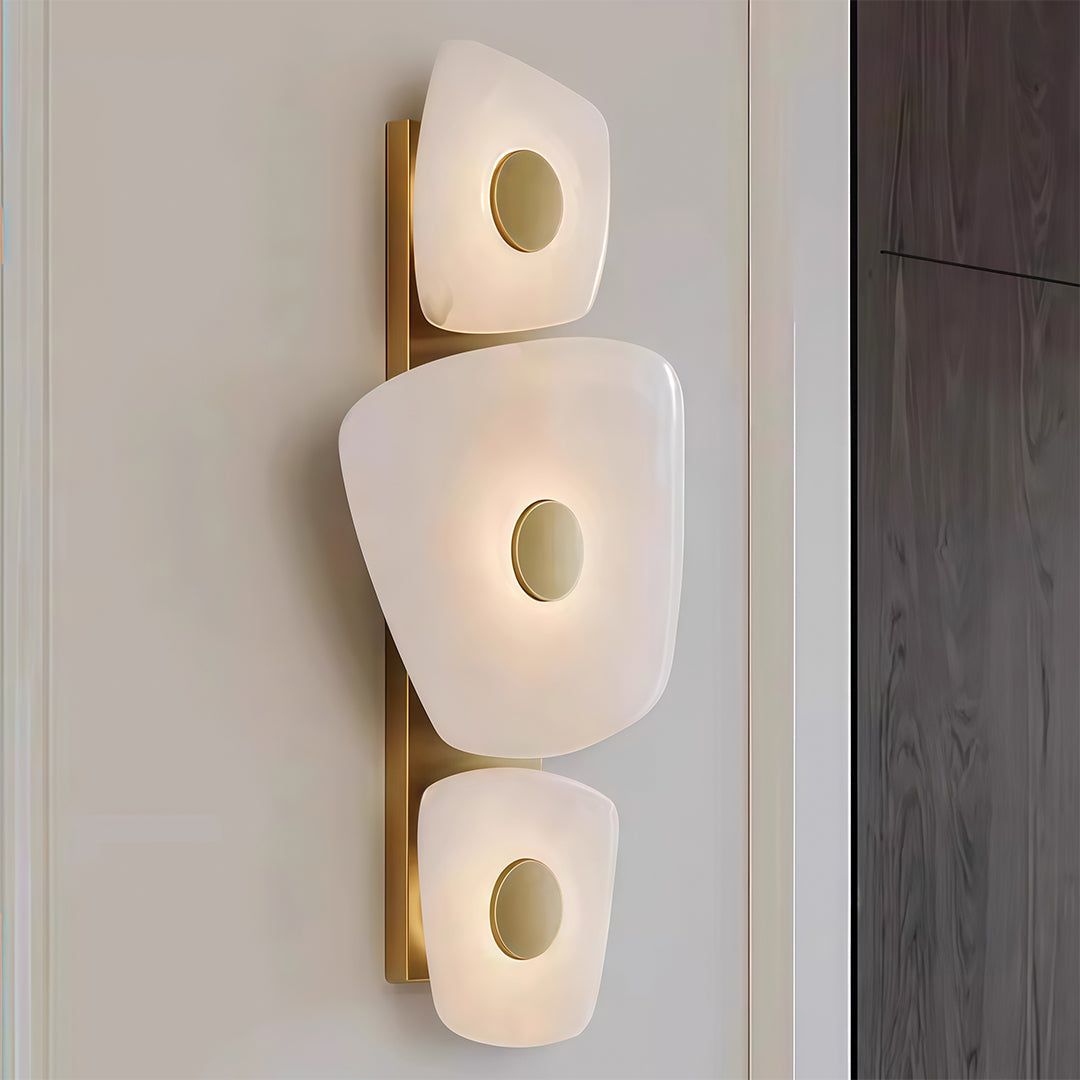 Architectural wall art lighted with glass shade chandelier styling providing artistic illumination beside dark wood architectural element.