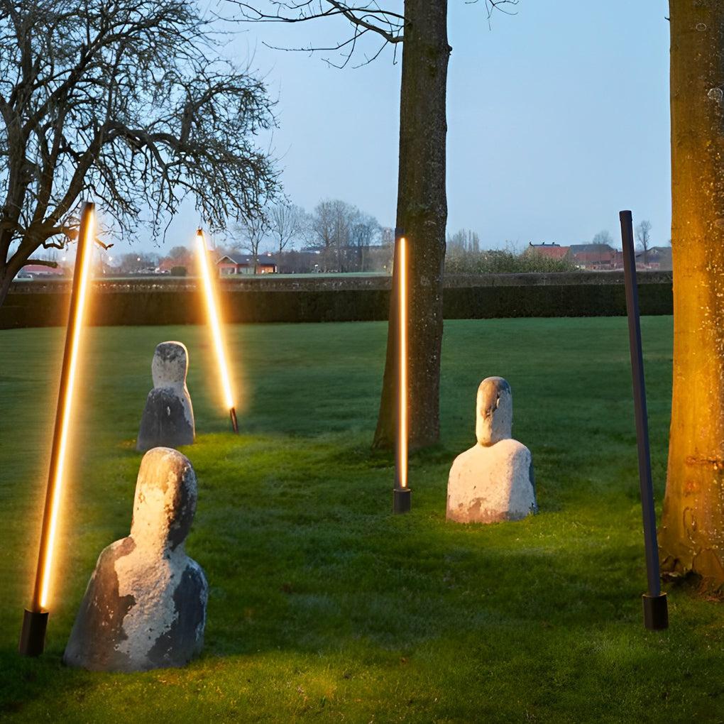 Artistic contemporary outdoor floor lamps installed at angles in a landscaped lawn setting.