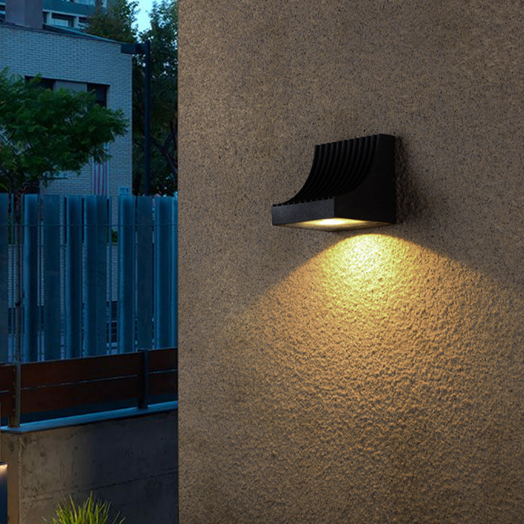 Close-up view of bronze outdoor light fixture showing curved arm and mounting details