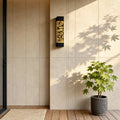 Contemporary led linear wall light installed on a beige exterior wall beside a plant, creating warm vertical lighting.