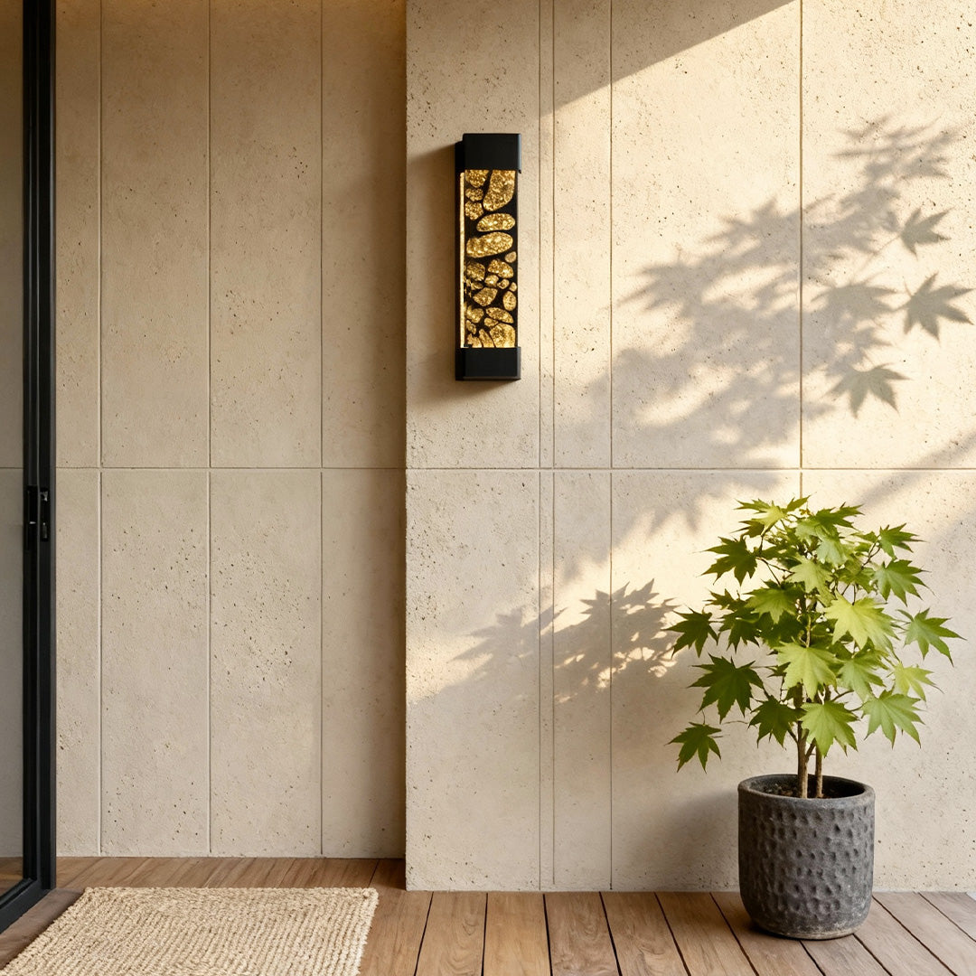Contemporary led linear wall light installed on a beige exterior wall beside a plant, creating warm vertical lighting.
