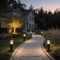 Black bollard garden lights illuminating a modern garden pathway with warm ambient glow.