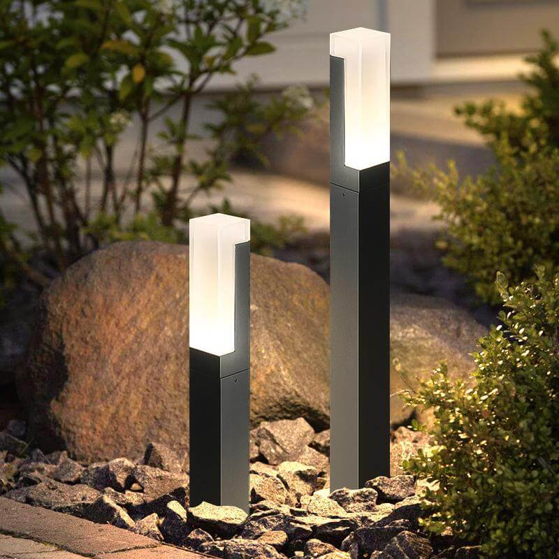 Black bollard lights installed in outdoor landscape near rocks