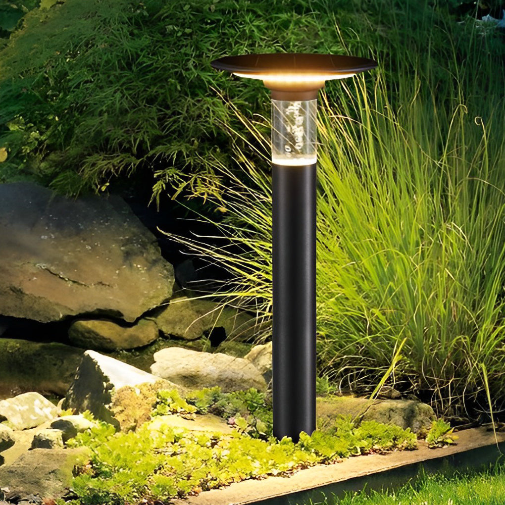 Black brass path lights illuminating a minimalist outdoor garden with focused glow.