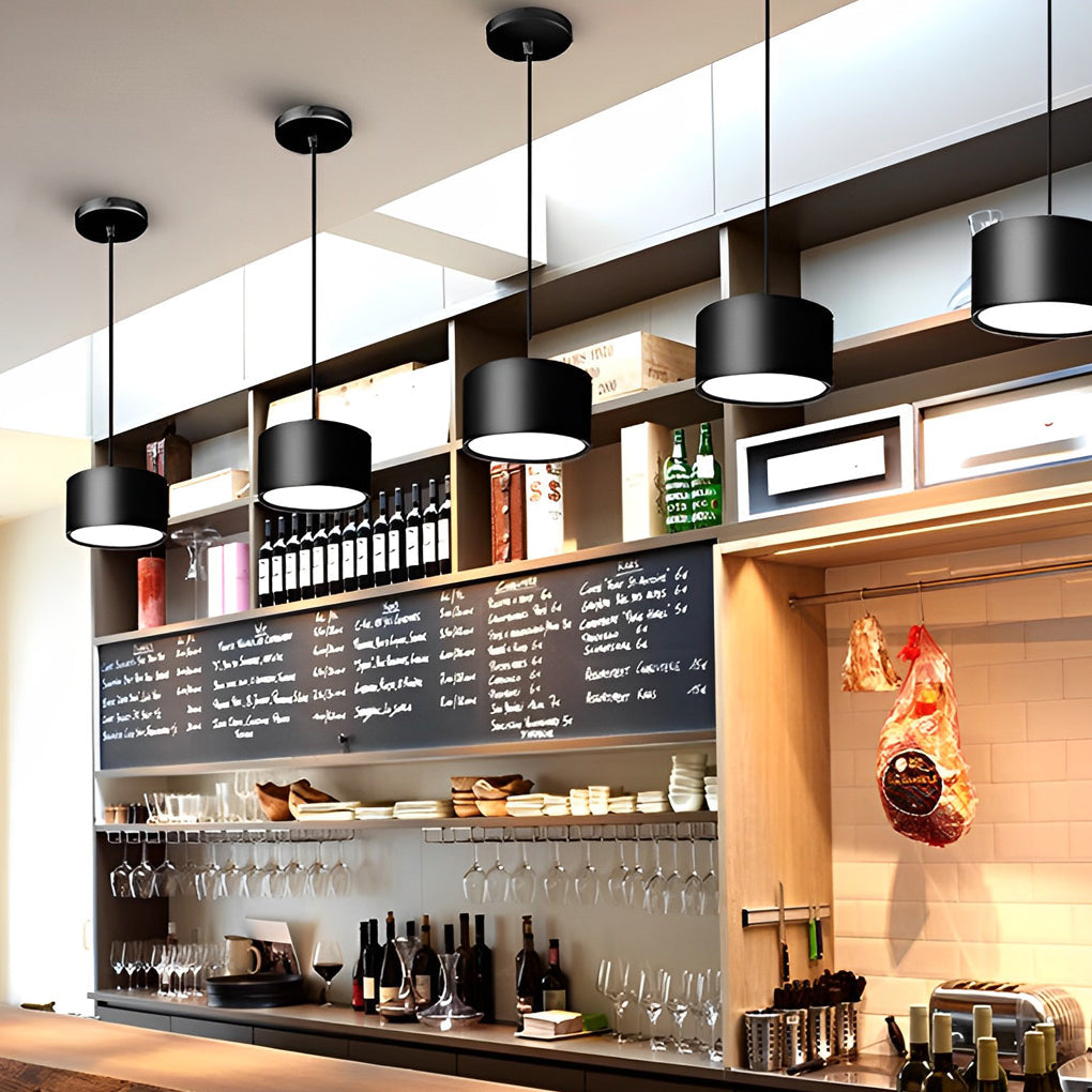 Black drum pendant light providing soft illumination above a stylish dining table.