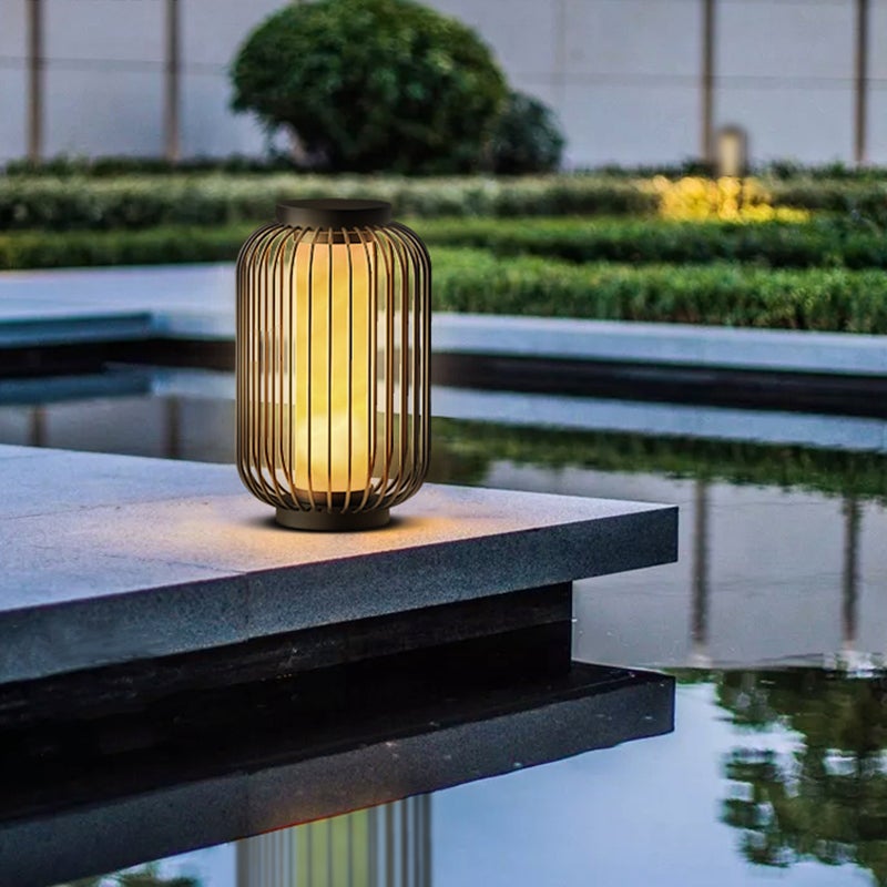 Lantern metal outdoor light with black frame, placed on wooden deck for contemporary outdoor illumination.