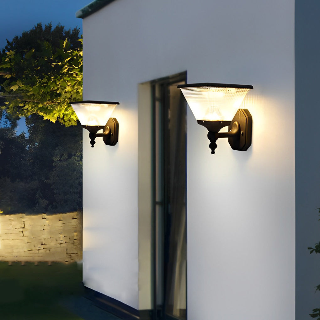 Black funnel wall light fixture attached to a white wall, casting a soft glow near a residential entrance.