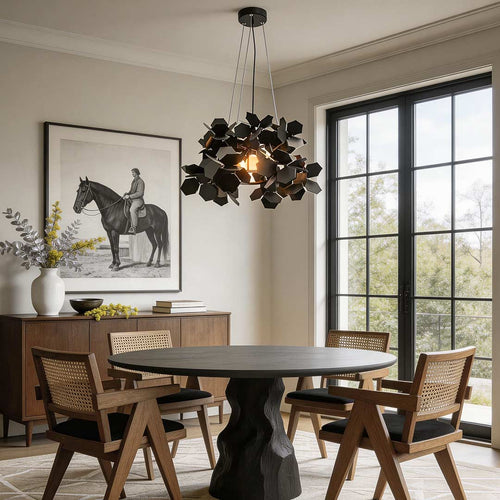 Black geometric chandelier with a leaf-inspired design, hanging above a modern dining table.
