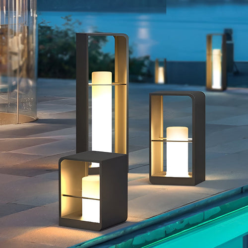 Black lantern outdoor light with open frame design, illuminating poolside area in the evening.