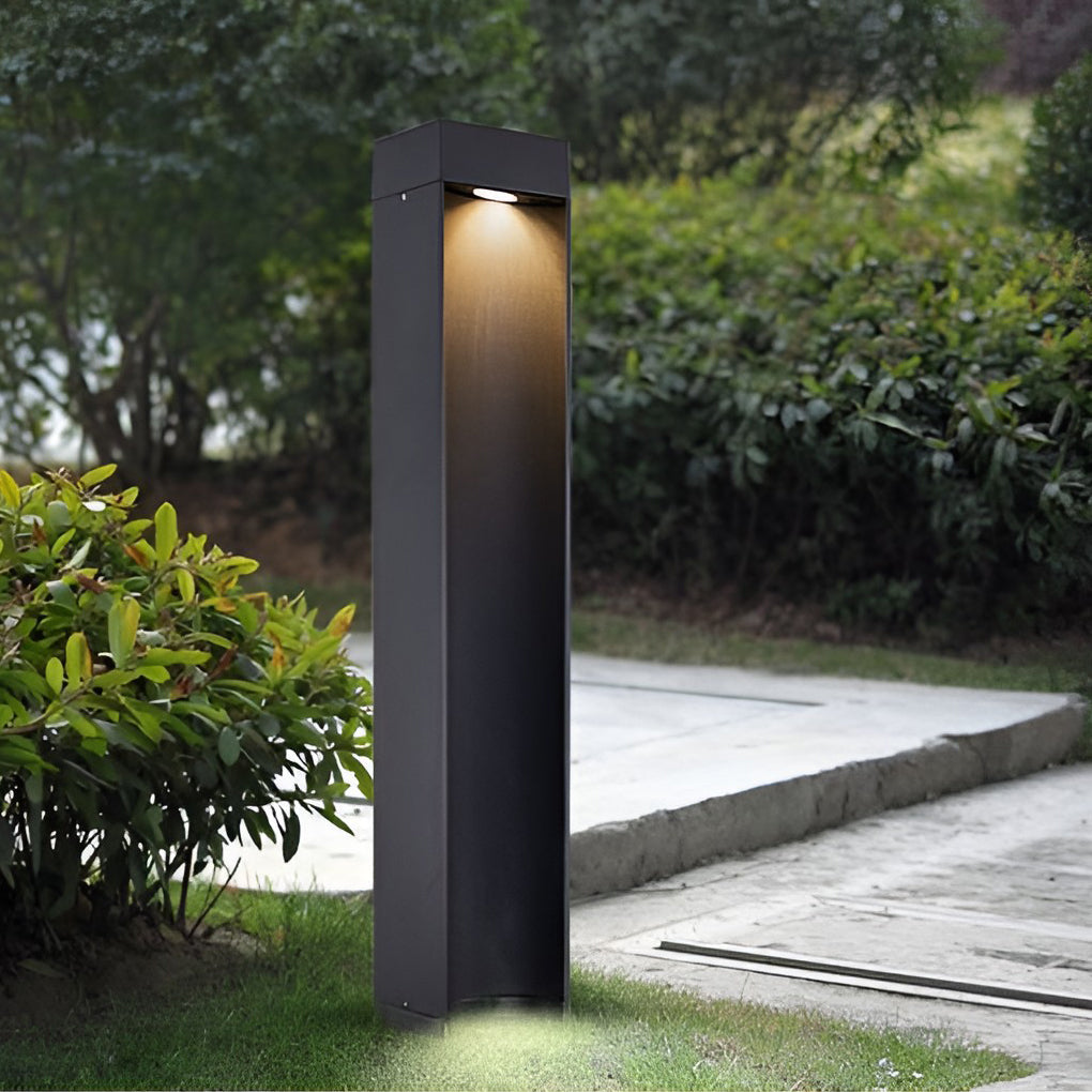 Black LED bollard light illuminating grass area with warm downward beam.