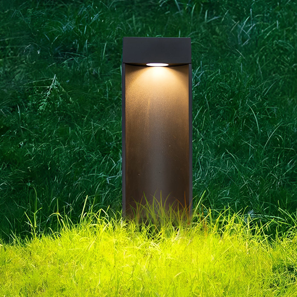 Black LED bollard light illuminating lawn grass with downward focused lighting.