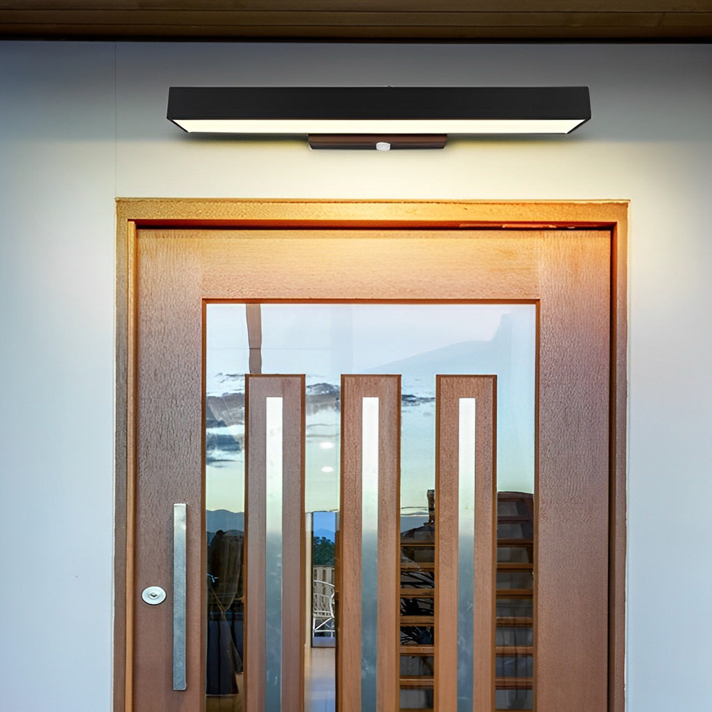 Black LED linear wall light installed above a framed entrance door, delivering clean lines and balanced illumination.