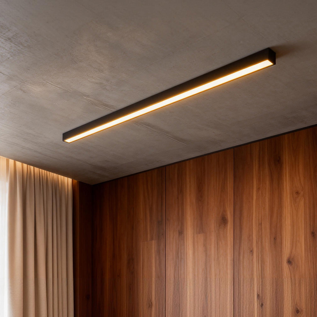Black linear ceiling light mounted above wood panel ceiling in contemporary space.