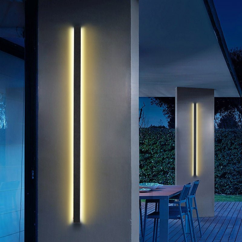 Black linear wall light providing warm illumination in a contemporary interior.