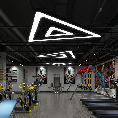 Multiple black modern chandeliers creating an artistic lighting display in an industrial interior.