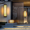 Black outdoor sconce light with wooden frame and grid design mounted on modern exterior wall.
