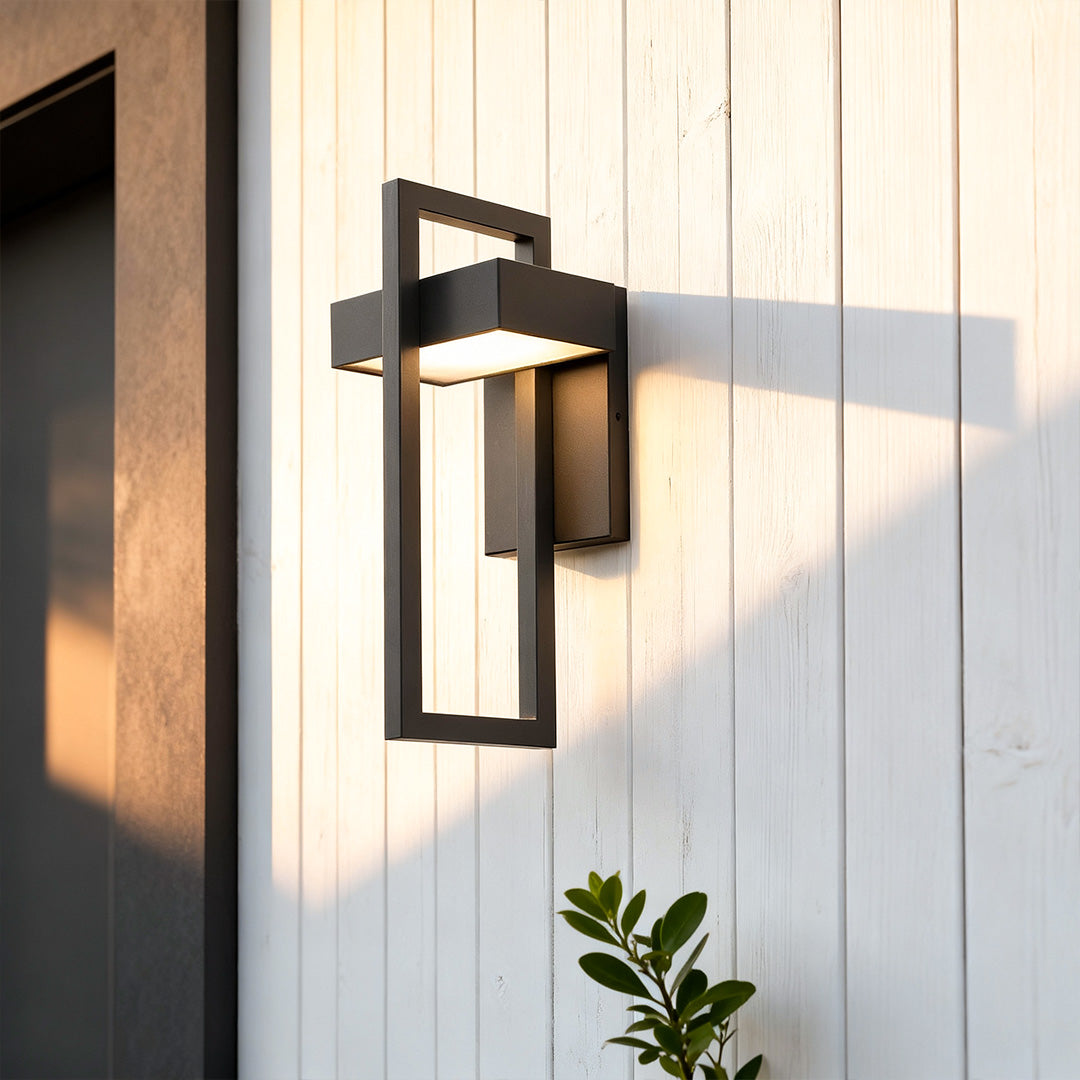 Black outdoor wall sconce modern installed beside a stone exterior door, emitting warm ambient lighting.