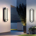 Black outdoor wall sconce mounted on a textured stone wall, adding a touch of modern design to the outdoor ambiance.