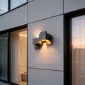Black up down wall lights with a modern geometric design, mounted beside a large window.