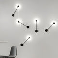Black wall light illuminating a modern living room with warm directional glow.