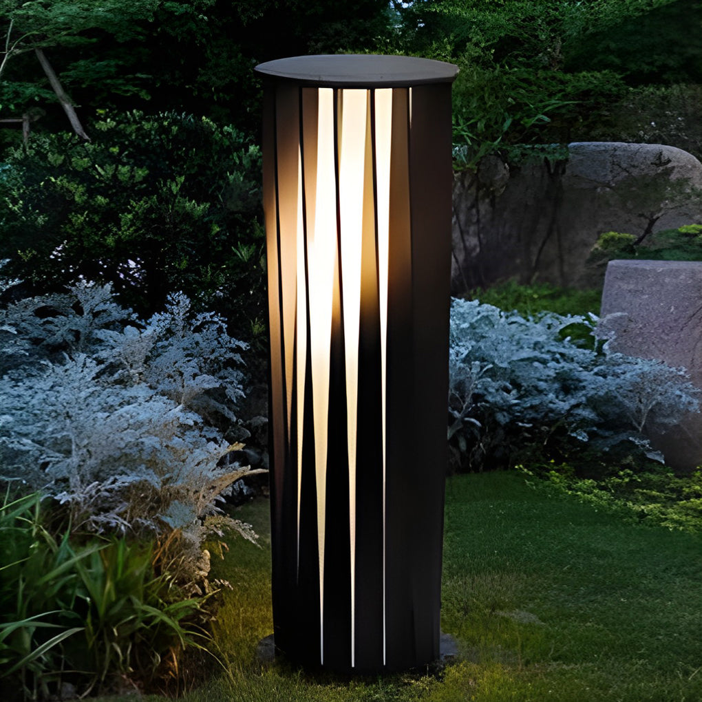 Single bollard path light placed on lawn highlighting surrounding plants.