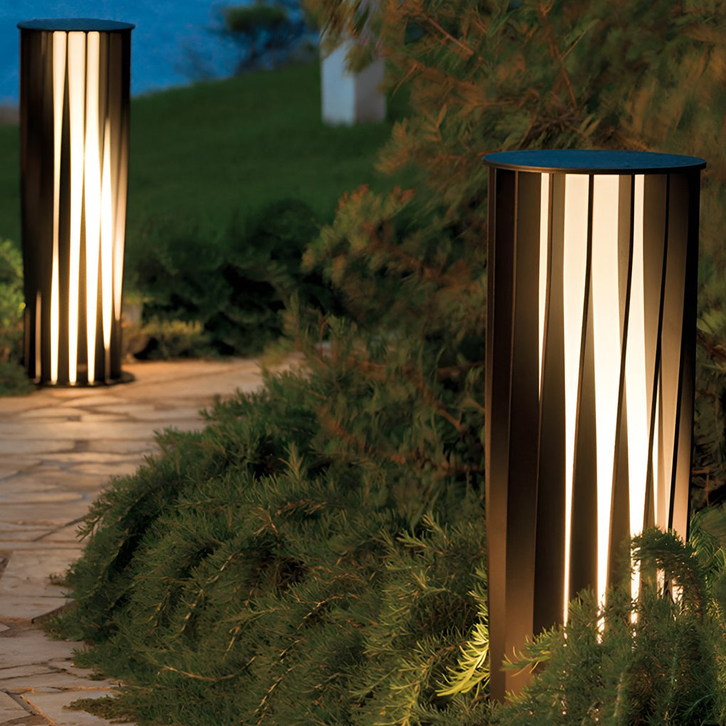 Outdoor bollard path light installed near shrubs providing soft ambient lighting.