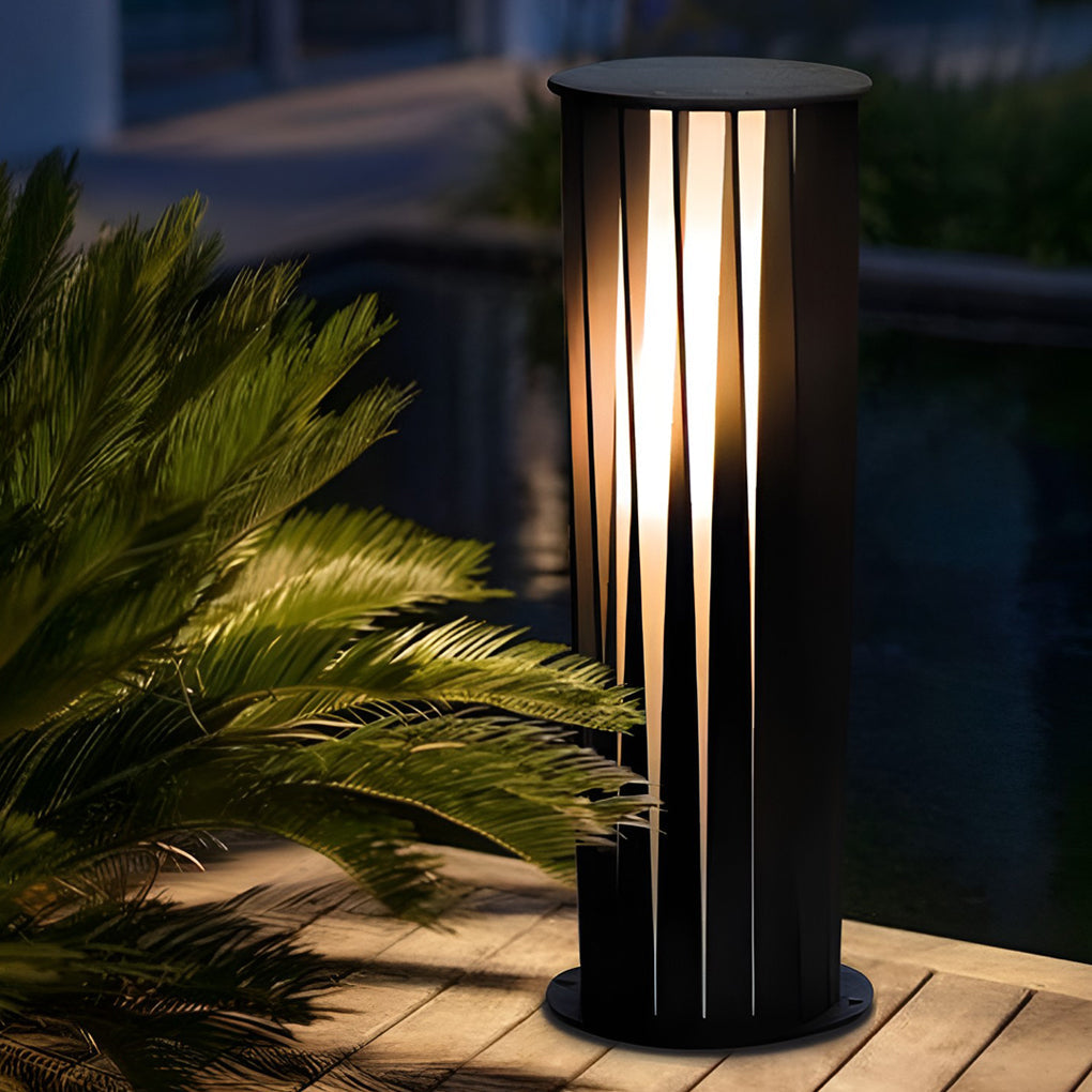 Cylindrical bollard path light illuminating plants with vertical light pattern.