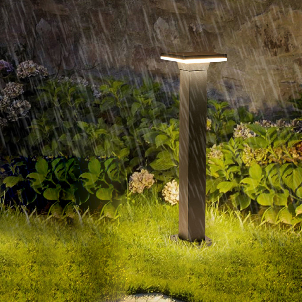 Black bollard pathway lights installed in grassy area, providing bright illumination during rain.
