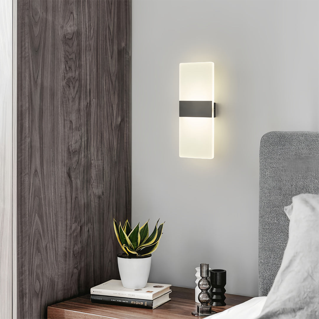 Brass wall lights mounted on wood-textured wall beside gray upholstered seating in modern residential space