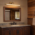 Brushed gold vanity light bar mounted above a rustic bathroom mirror