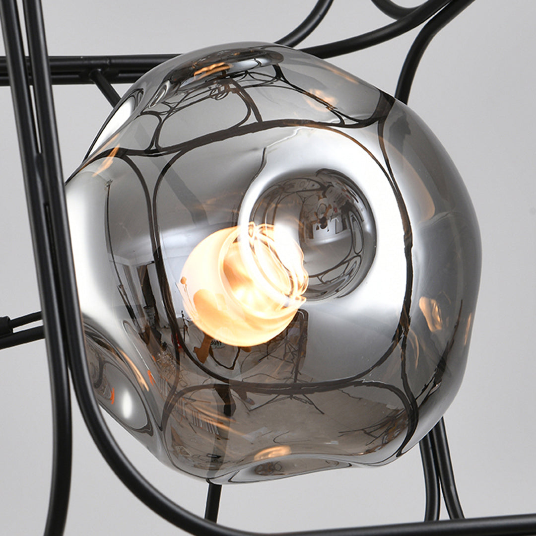 Close up of caged pendant light glass shade and bulb, showing detailed metal cage structure and warm glow.