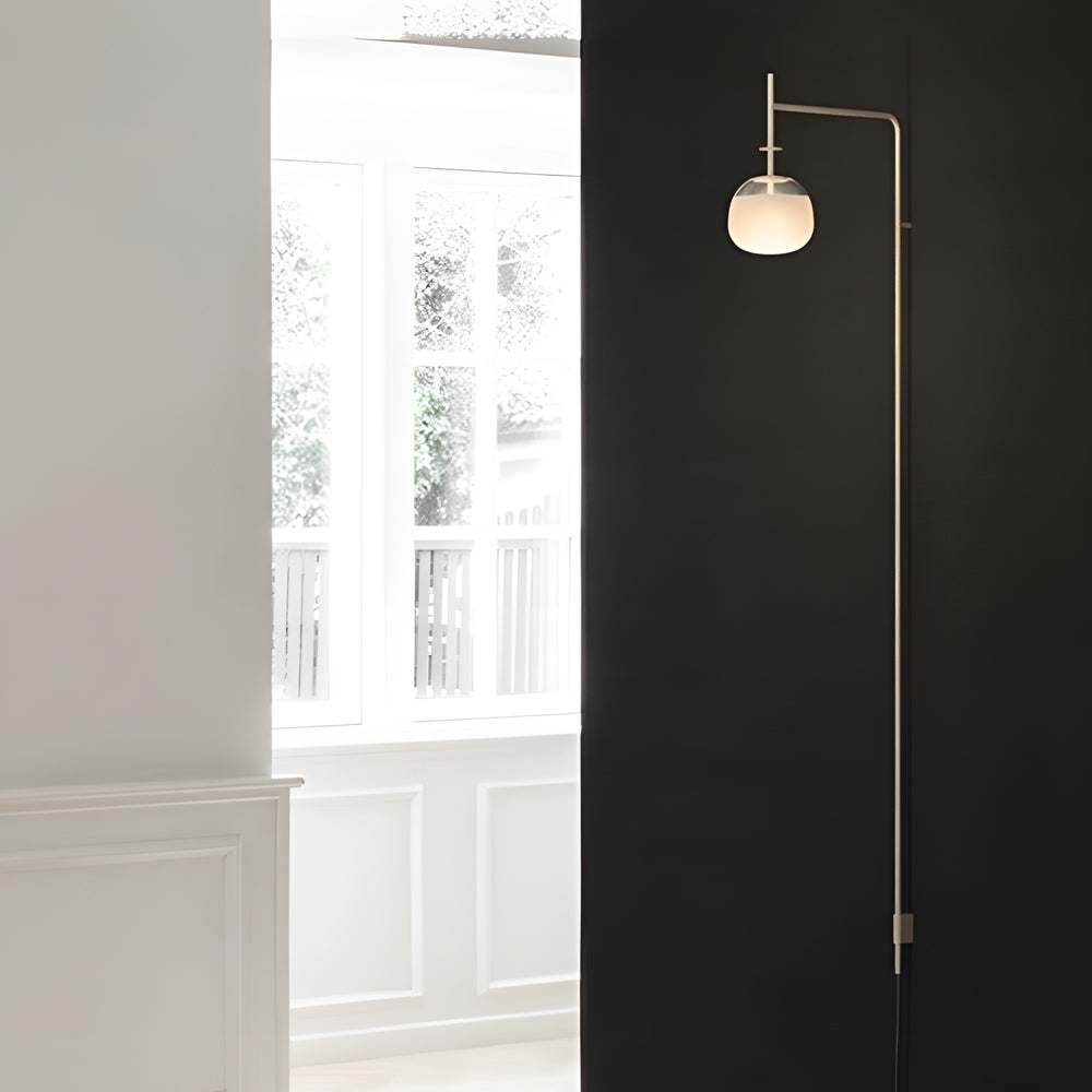 Modern cantilever wall lamp with globe shade positioned near a window, blending soft light with natural daylight.