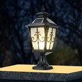 Cast aluminum post light with decorative bronze accents and frosted glass, mounted on a stone pillar.