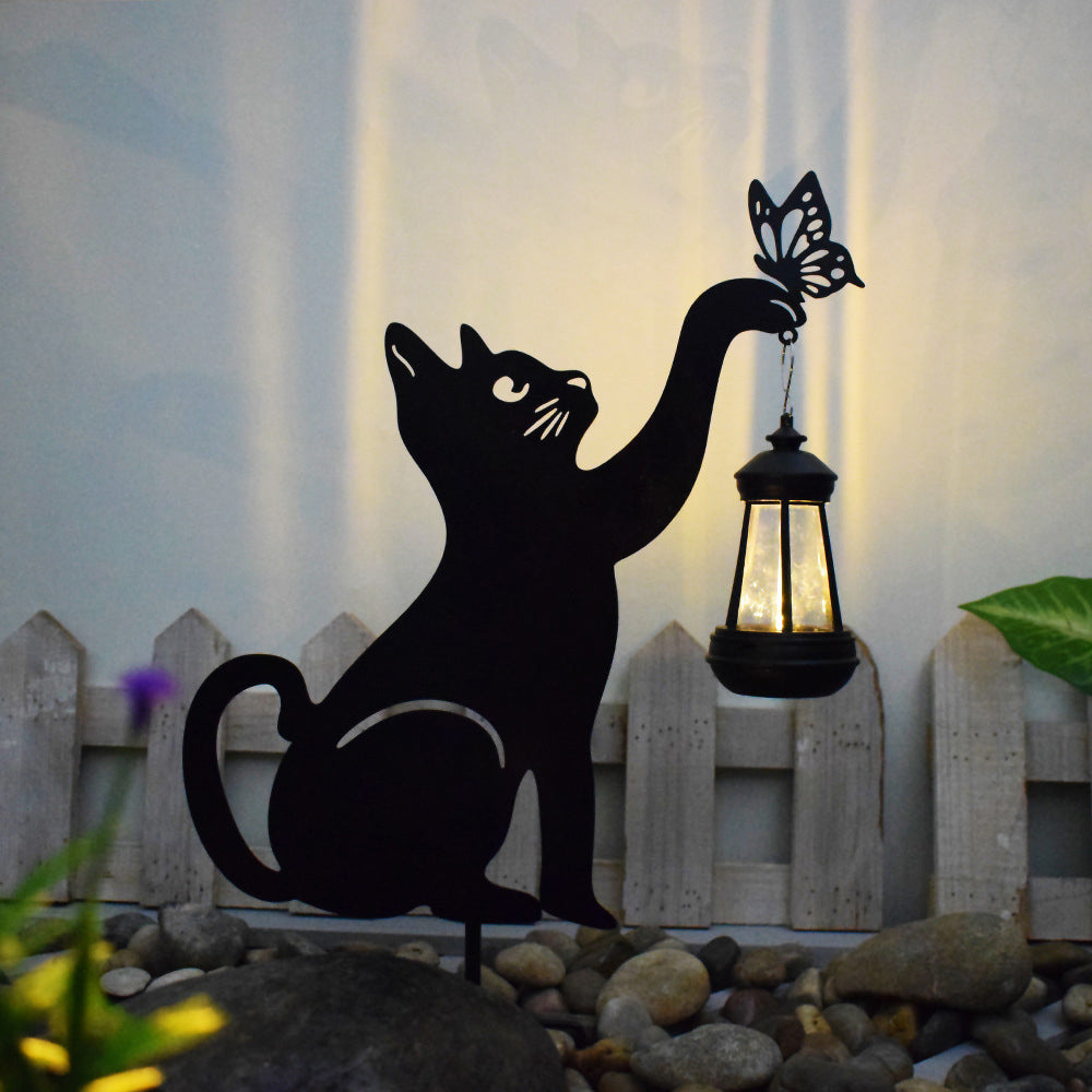 Cat silhouette light illuminating a cluster of lights in a garden.