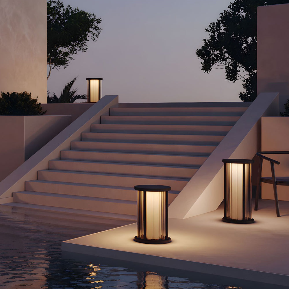 Minimalist outdoor steps illuminated by matching cylindrical lanterns creating sophisticated pathway lighting design