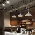 Cement pendant light hanging above bar counter in café interior, creating warm industrial ambiance.