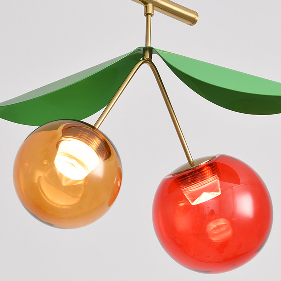 Close-up detail of cherry pendant light showing individual red and amber glass spheres with brass connecting hardware