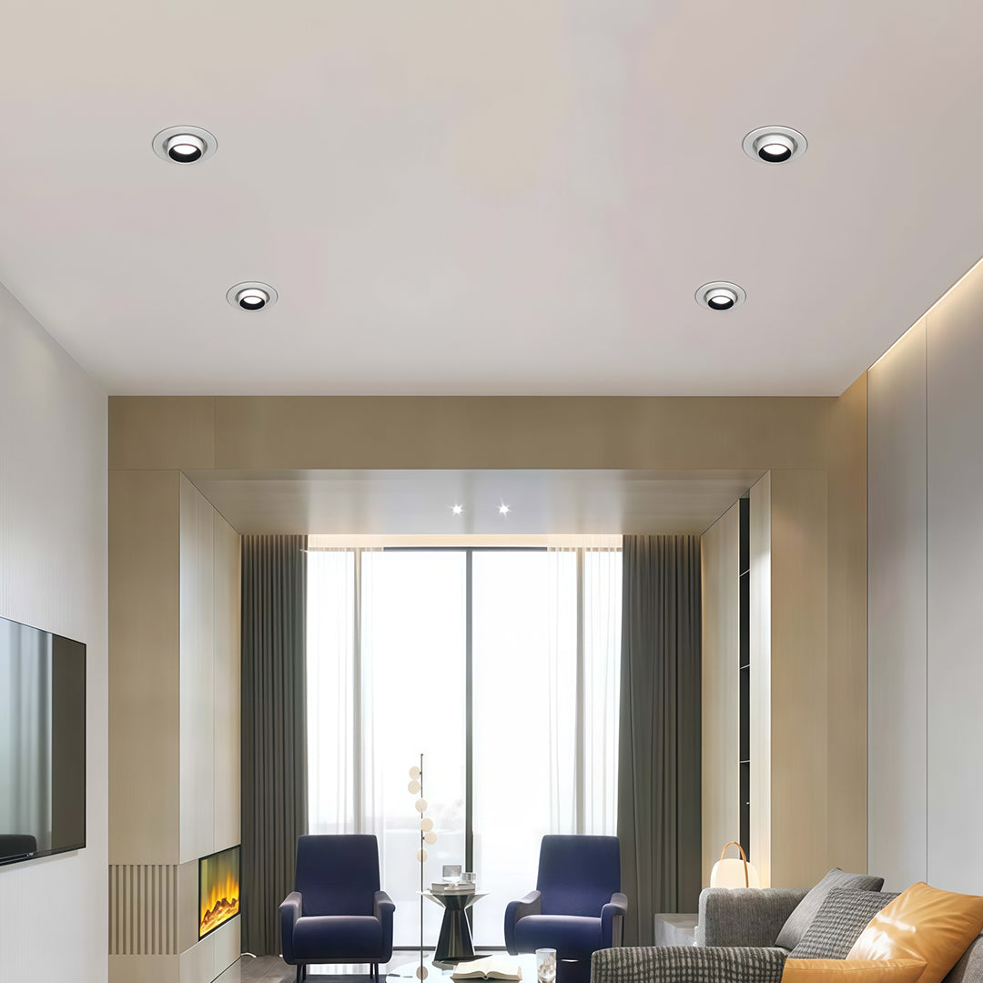 Multiple chrome-finish LED ceiling downlights installed in a spacious living room with large windows.