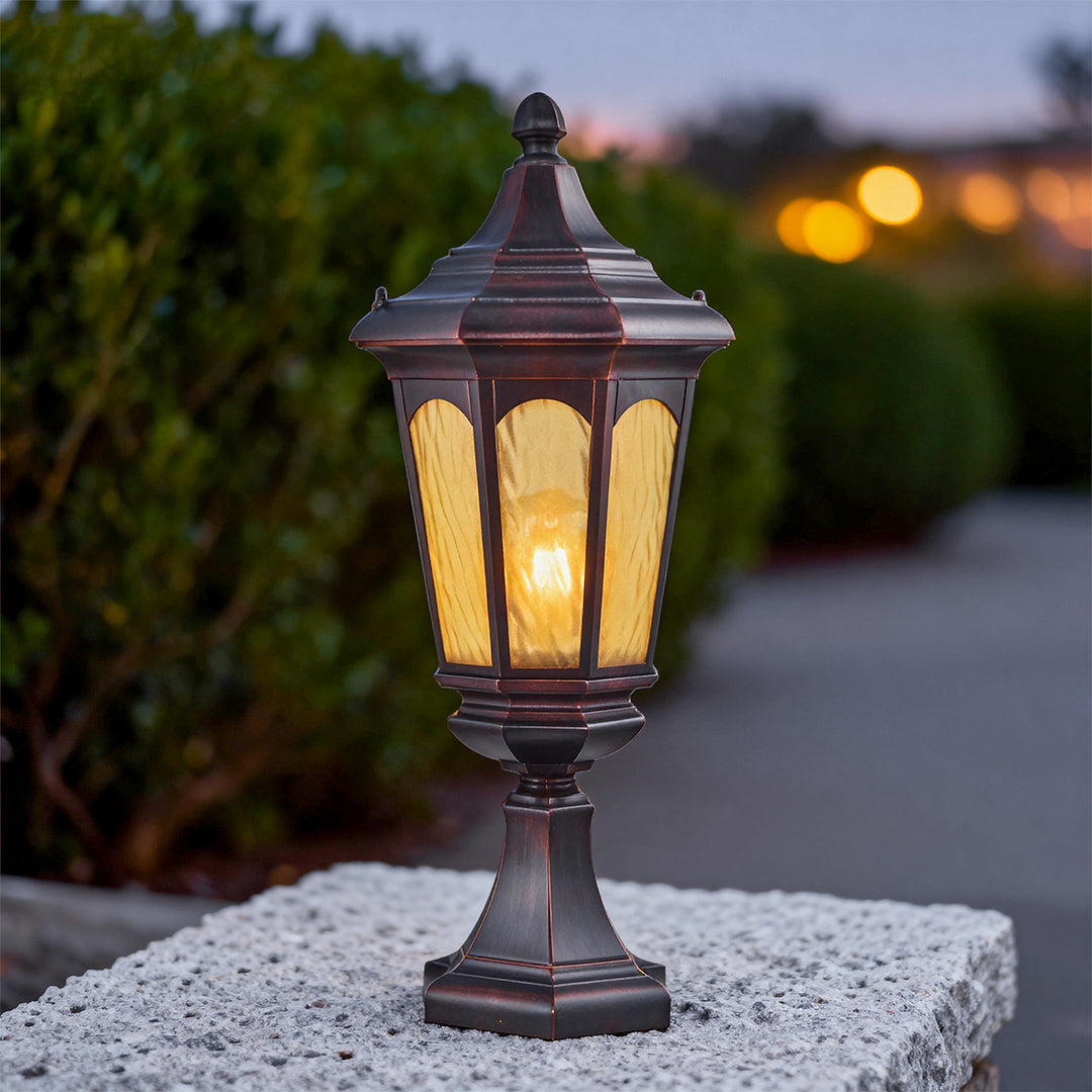 Classic residential pillar light providing soft illumination on gravel surface with blurred bokeh background