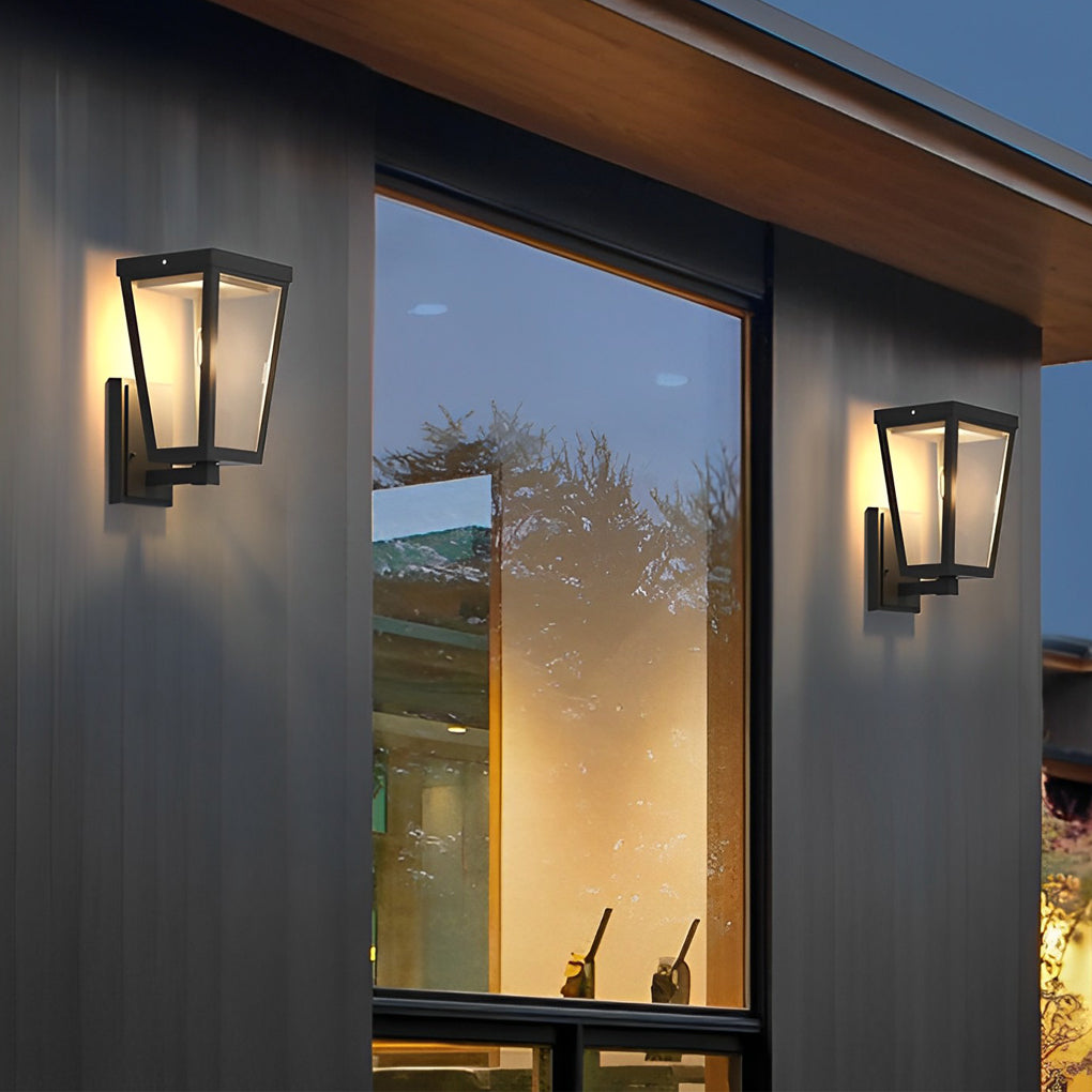 Close-up of exterior LED wall lantern with black frame and clear glass, casting a soft glow.