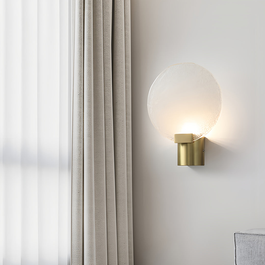 Close-up of a round wall light with a frosted glass shade and gold base, highlighting its sleek design.