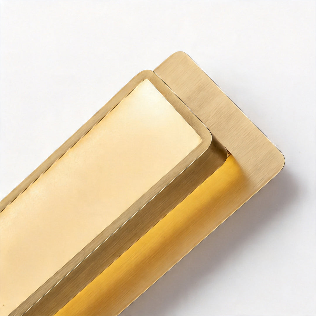 Close up view of the sleek gold wall light fixture with a metallic shade on white background.