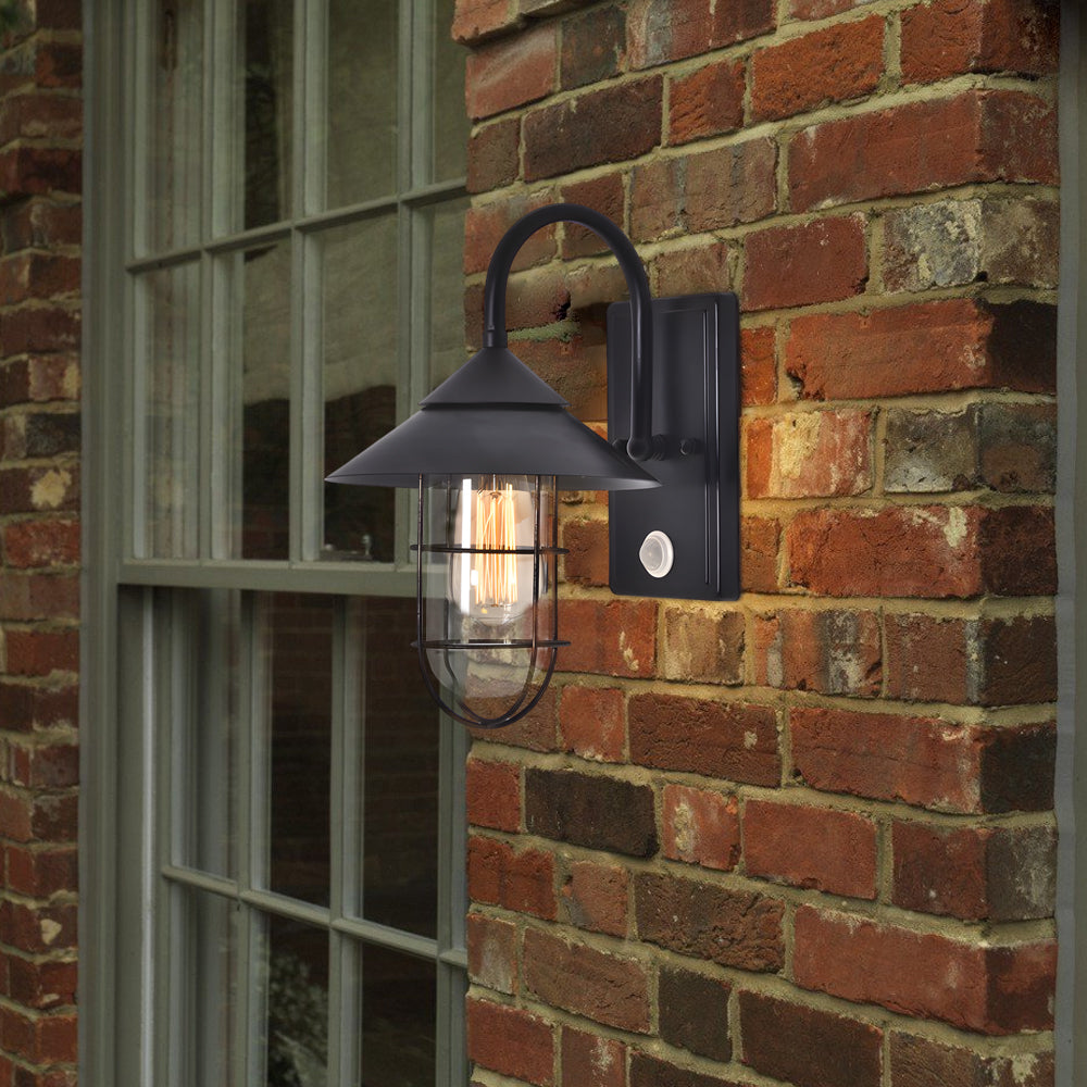Close-up of black barn wall light with clear glass shade, showcasing its sturdy metal construction.